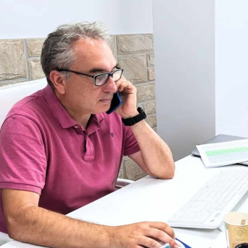 Alberto, Director Financiero de Abogados El Cañaveral, sentado en su mesa de trabajo, comprometido en una conversación telefónica.