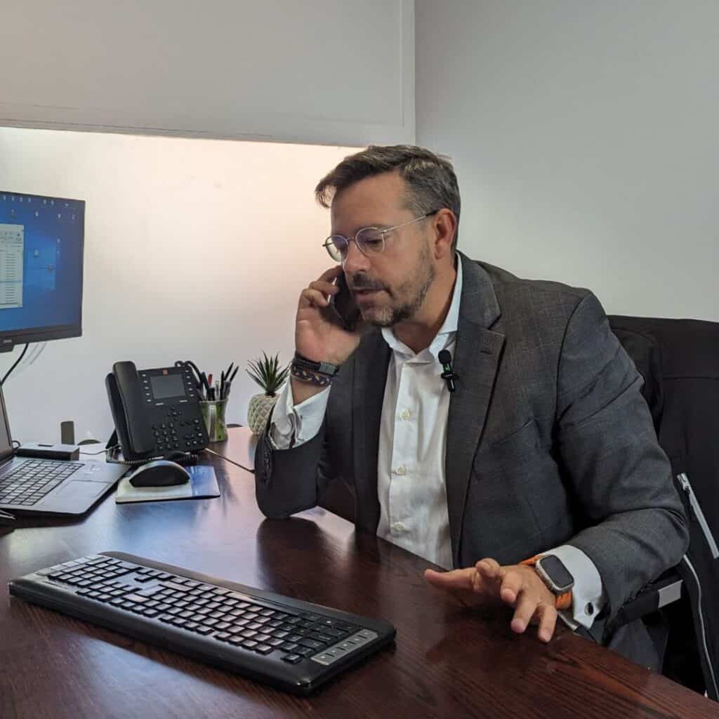 Pablo, Socio Fundador de Abogados El Cañaveral, sentado en su oficina, hablando por teléfono y gestionando un caso legal.